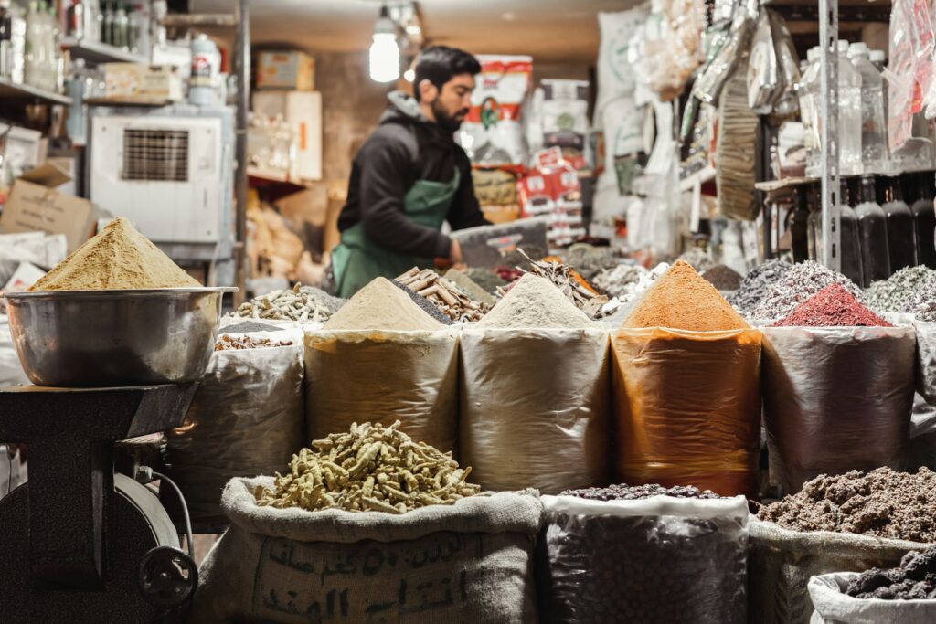 Gewürzhändler hinter bunten Gewürzen in einem iranischen Bazar
